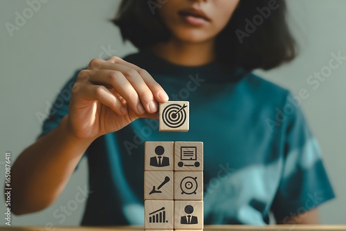 Woman builds a goal oriented business strategy with wooden blocks for success and achievement with a motivational future vision