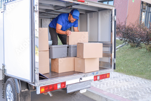 an employee in a blue uniform loads a truck with boxes for transportation. concept logistics, small business