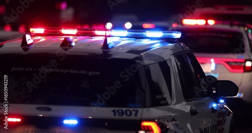 Police units respond to the scene of an emergency with illuminated red and blue lights at dusk.