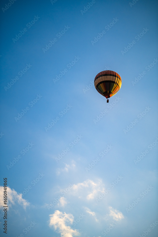 Obraz premium Colorful Hot Air Balloon Flying Against a Clear Blue Sky