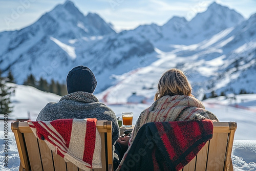 Couple enjoying winter landscape from a snow covered terrace with mountain view