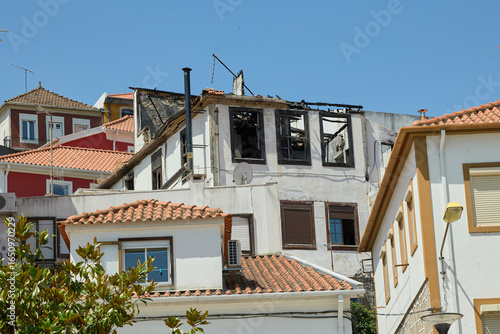 Burned house ruins with damaged roof.