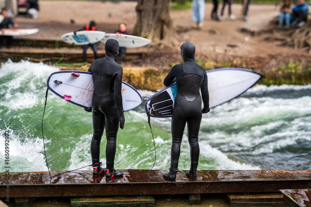 Obraz premium Par de surfistas preparandose para ingresar a la Eisbachwelle, en la ciudad de Munich