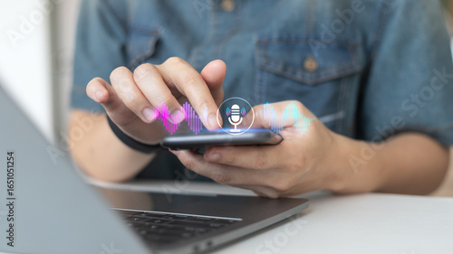 Person using smartphone with hologram microphone and soundwave icons, representing voice recognition, speech to text, and AI assistant technology.
