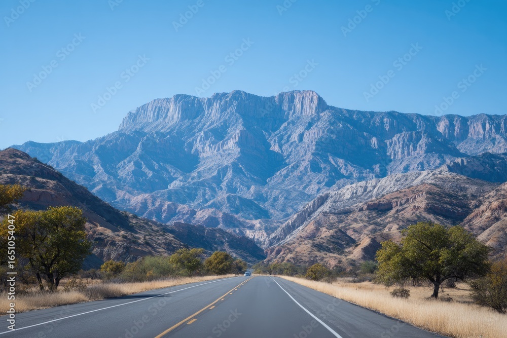 Fototapeta premium Wide road stretches through stunning mountainous landscape under
