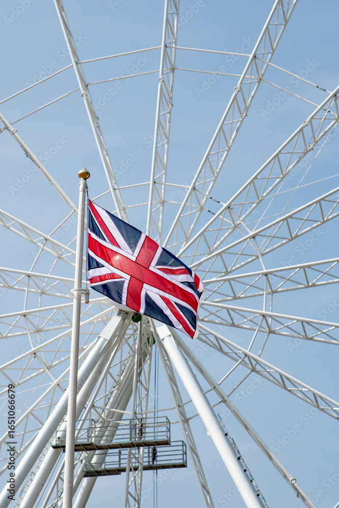 Fototapeta premium Union jack flag flying against a white ferris wheel background. Great Britain concept. Business.