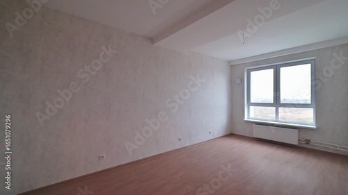 Empty room with wooden floor, gray walls, window, and radiator. Minimalist interior