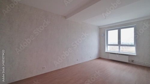 Empty room with wooden floor, gray walls, window, and radiator. Minimalist interior