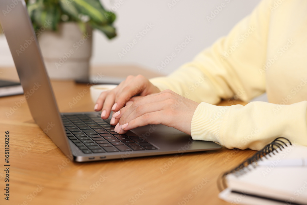 Fototapeta premium Copywriter using laptop at wooden table indoors, closeup