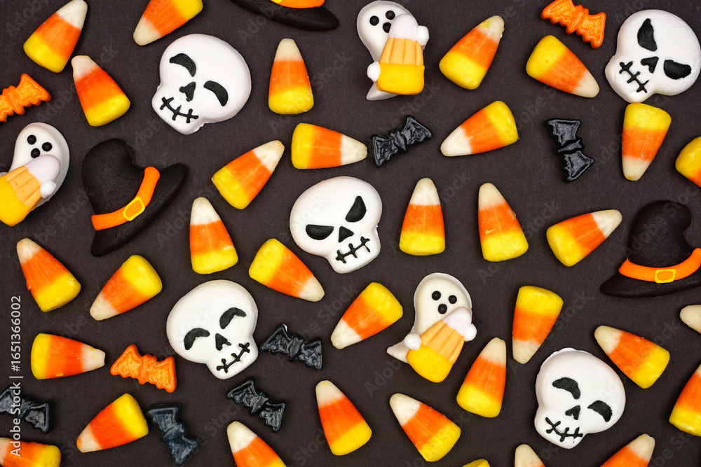 Fototapeta premium Halloween candy background. Top down view flat lay against a black background.