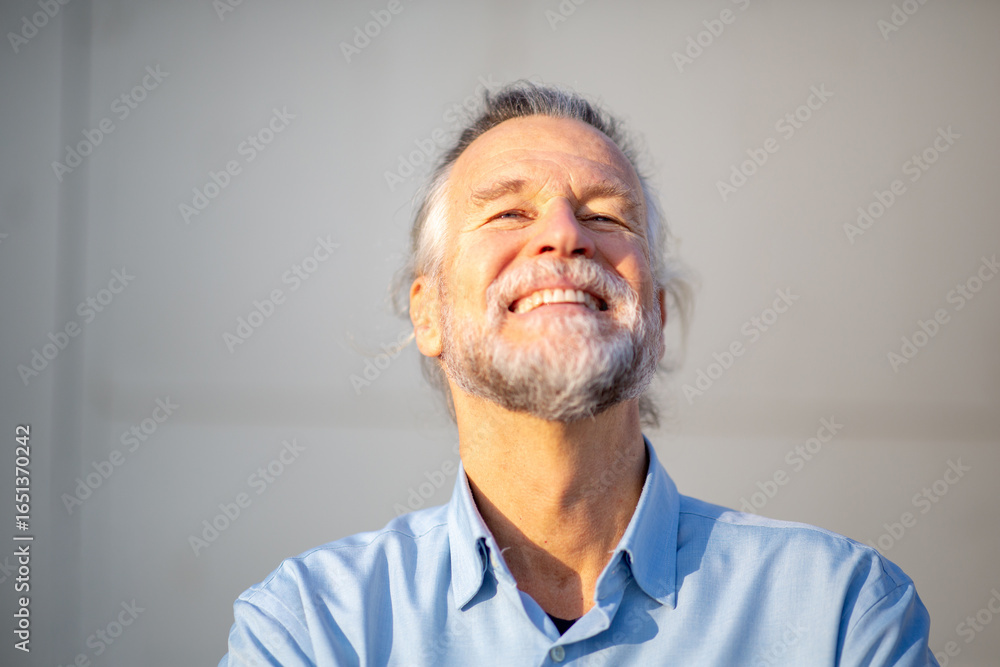 Obraz premium Joyful senior man smiling broadly under warm sunlight