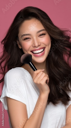 Young Woman Laughing Mid-Motion Holding Makeup Brush Against Pink Background