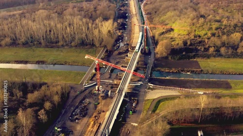 Aerial view of bridge construction site with crane in rural landscape