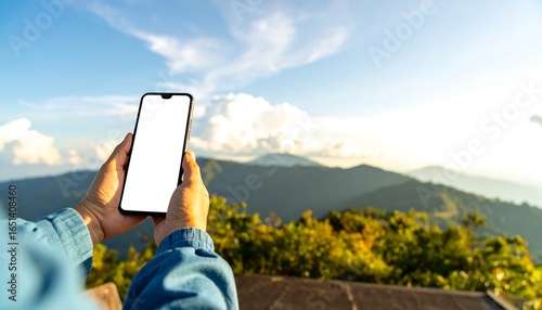 Smartphone held aloft with a blank screen, showcasing a mountain vista.