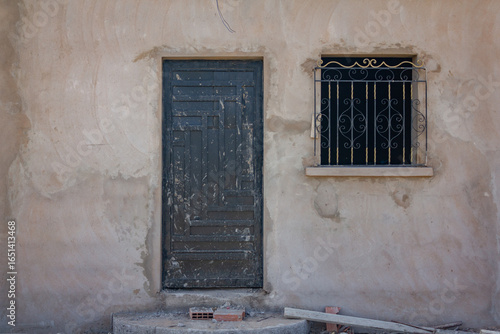 incomplete house showing a metal door beside a window