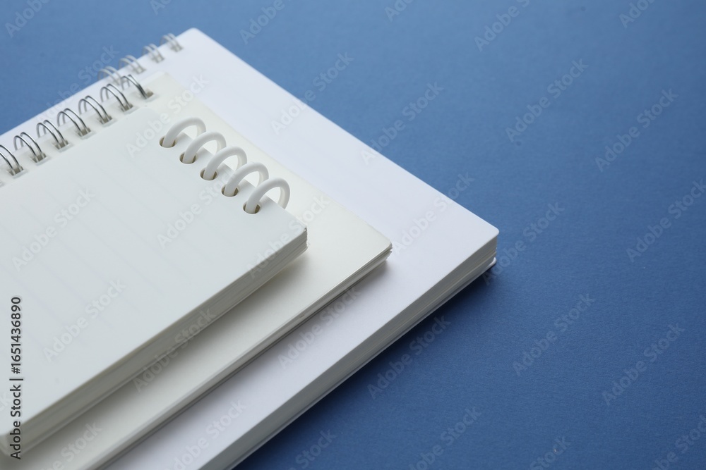 Three white notebooks on blue background, closeup Three white notebooks on blue background, closeup