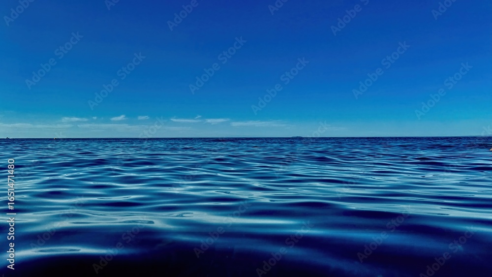 Obraz premium deep blue ocean water surface with gentle ripples under clear sky horizon ideal for background texture or calming design