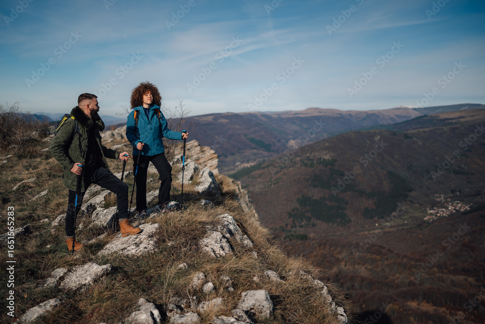 Obraz premium Hikers standing on mountain top enjoying scenic valley view