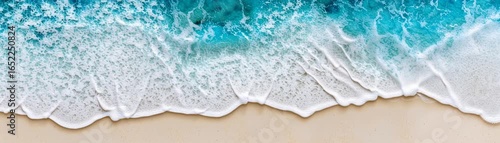 Expansive sandy shoreline meets the rhythmic dance of ocean waves under a clear sky creating a serene and tranquil coastal landscape scene.