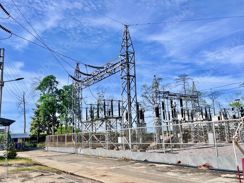 High voltage electrical substation with transformers and power lines under blue sky, energy infrastructure for electricity transmission and distribution.