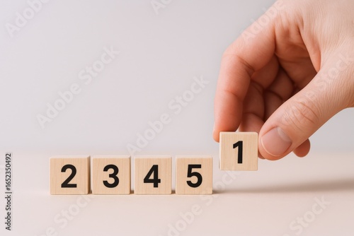Hand placing number one tile in sequence of five, conceptual of leadership and achievement