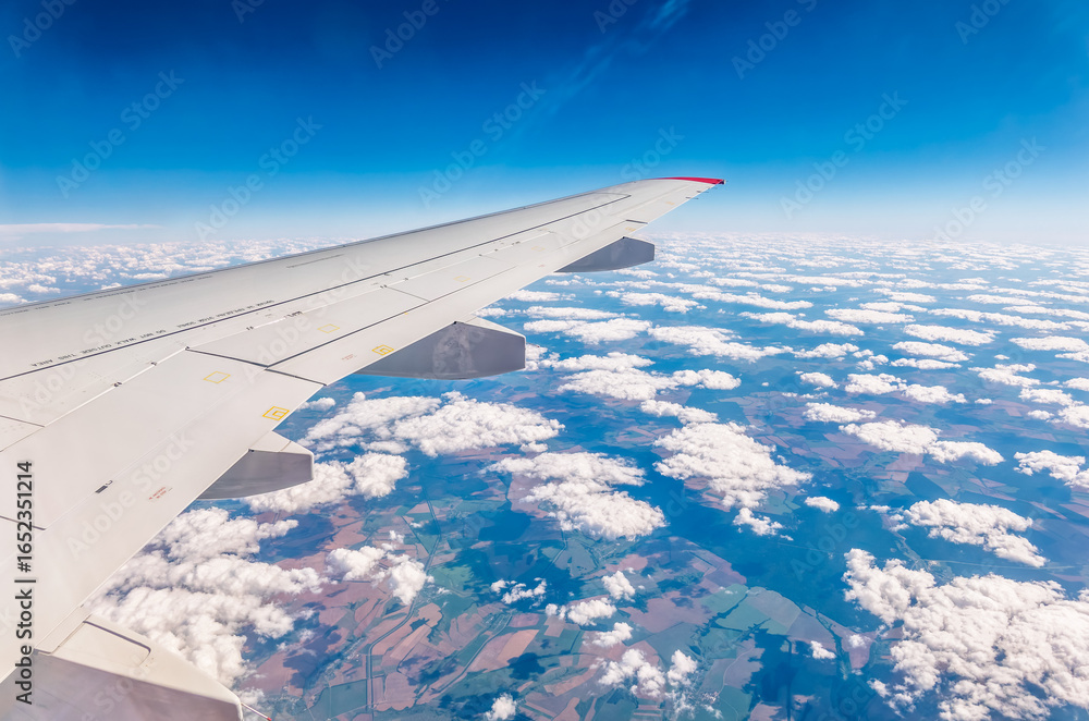 Fototapeta premium View from the airplane window at a beautiful cloudy sky and the airplane wing