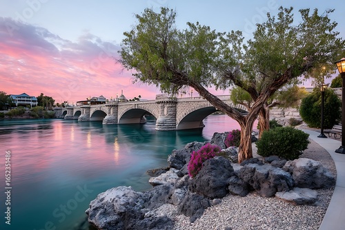 Vibrant sunset casting a warm glow on the iconic London Bridge replica in Lake Havasu City, Arizona, surrounded by calm waters and lush trees.