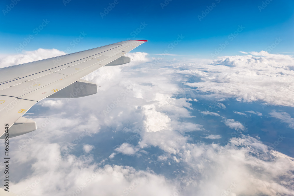 Fototapeta premium View from the airplane window at a beautiful cloudy sky and the airplane wing