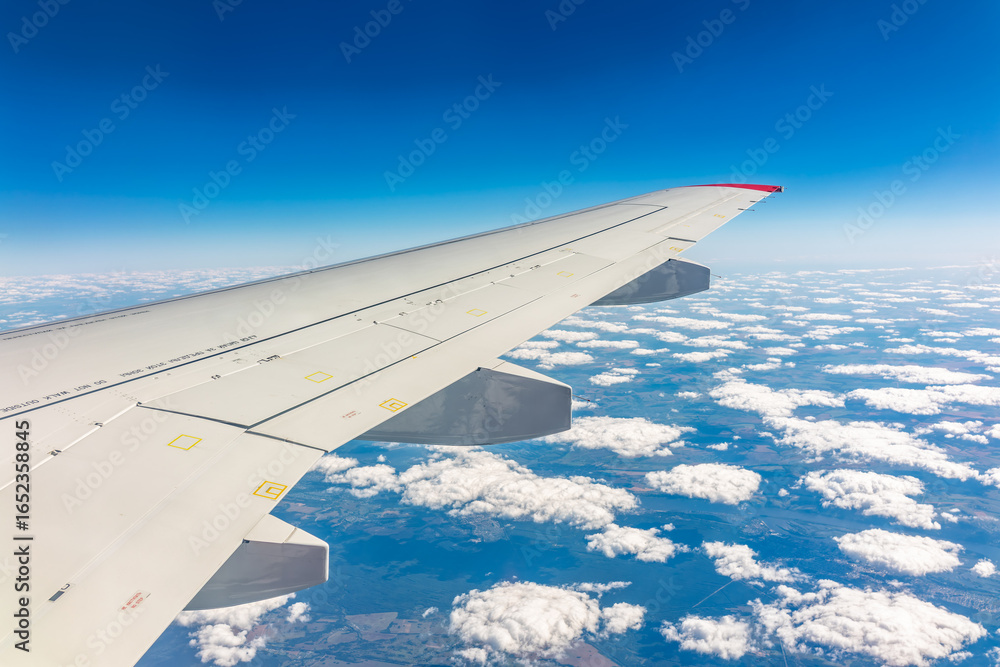 Fototapeta premium View from the airplane window at a beautiful cloudy sky and the airplane wing