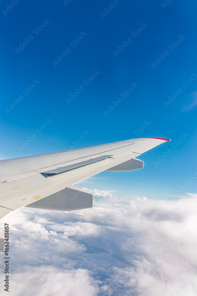 Fototapeta premium View from the airplane window at a beautiful cloudy sky and the airplane wing