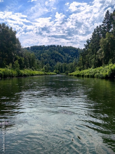 Scenic River Flowing Through Lush Green Forest Under a Cloudy Sky, Perfect for Outdoor Activities