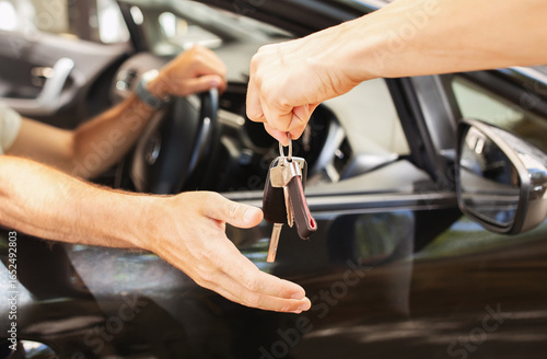 Obraz na plátně Hands of valet parking worker giving key to driver man sitting inside car