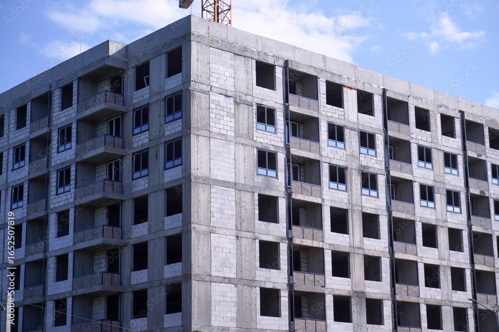 Fototapeta premium Construction site of modern residential building with crane in background