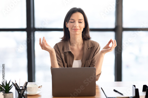 Mental Hygiene. Calm beautiful girl meditating at workplace, dealing with stress and anxiety. Empty space