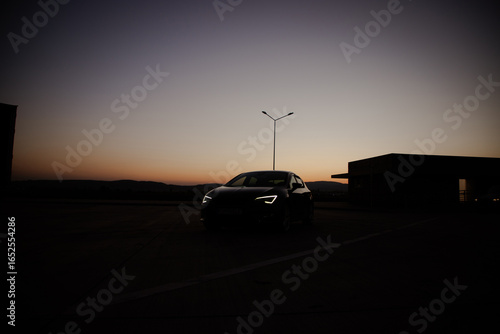 A modern black sport car in the sunset