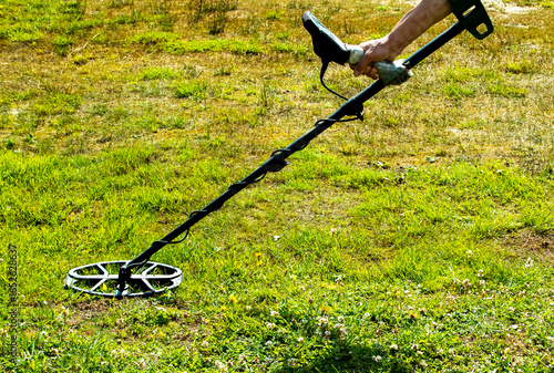 a man walks through a field with a metal detector