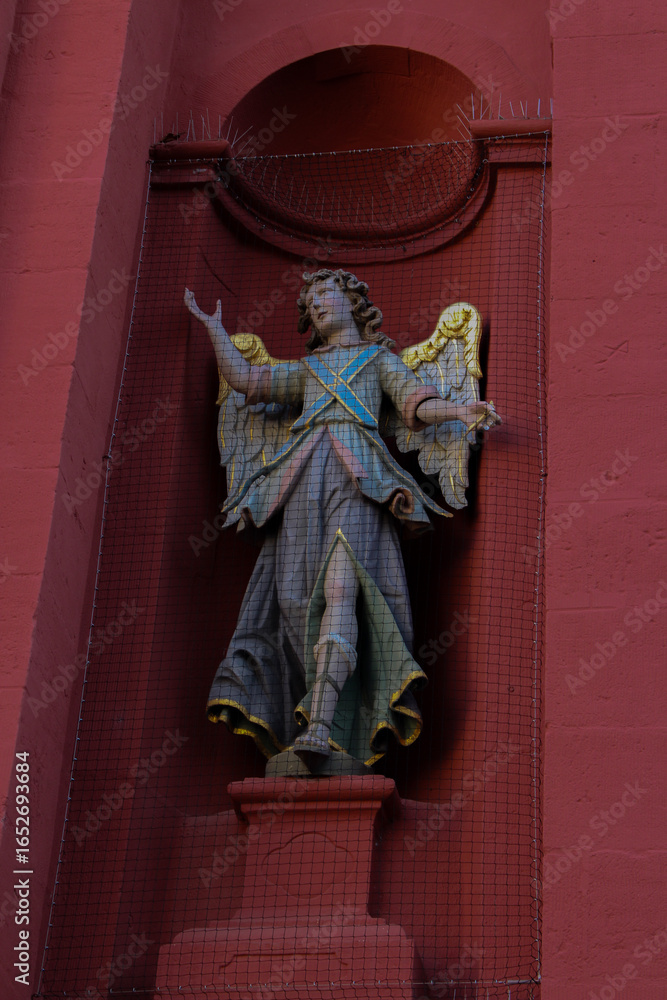 Fototapeta premium angel statue with golden wings at a red church