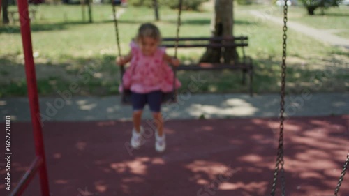 Young girl swinging at public park.