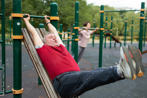 Konstfotografi elderly man doing exercises on a horizontal bar at an outdoor sports ground