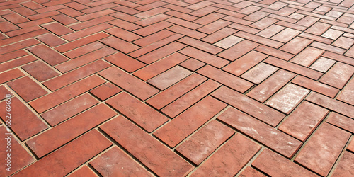 Reddish-brown brick pavers in herringbone pattern, showing natural color variations and weathered surfaces with traditional masonry construction appearance.