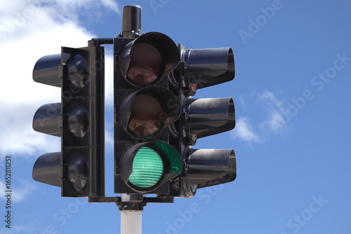 Green traffic light with the sky as background,