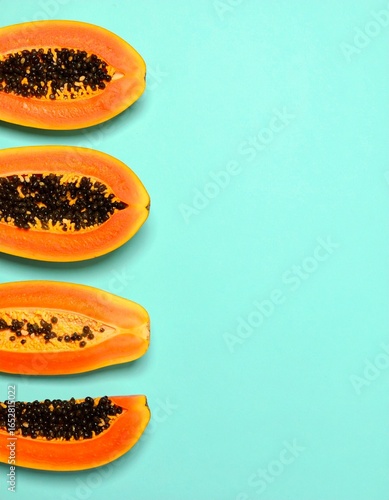 Four papaya slices arranged vertically against a teal background