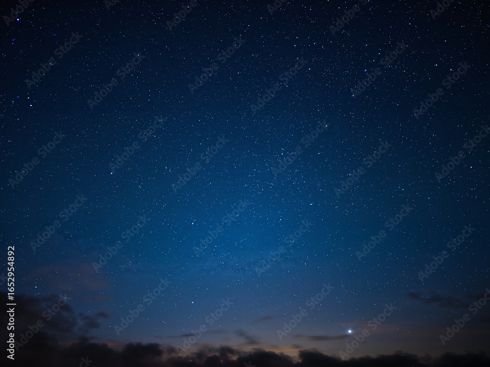 Fototapeta premium A beautiful night sky full of stars with clouds at the horizon. A concept for astronomy, space, or tranquility.