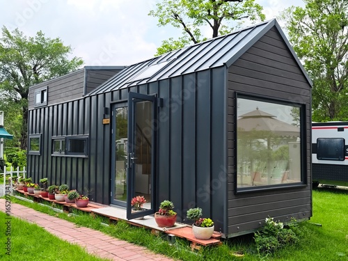 Quadro su tela Modern tiny house with garden and brick path, showcasing sustainable living and