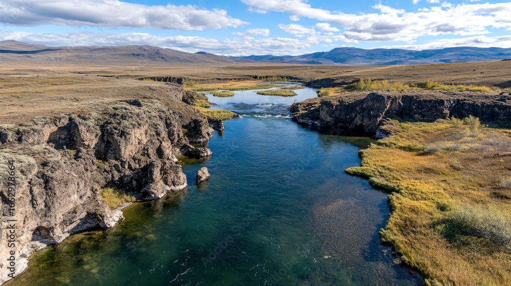 Fototapeta premium Aerial view of a deep river canyon with rocky cliffs and distant mountains.