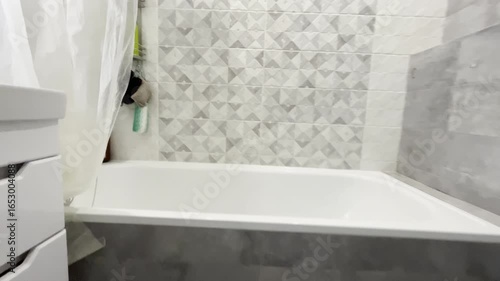 A modern bathroom design in gray tones, the camera smoothly approaches past the toilet and sink to the bathtub. High quality 4k footage