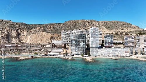 Fototapeta Naklejka Na Ścianę i Meble -  Panoramic view of a coastal city with modern buildings, sandy beach and clear blue sea under a bright sunny sky