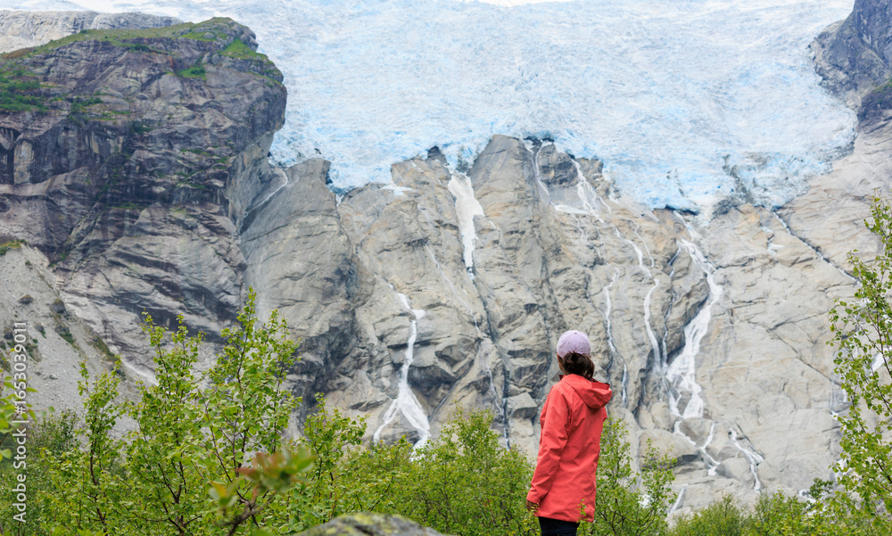 Naklejka premium an asian girl wearing pink outdoor coat looking at the glacier up in the mountain