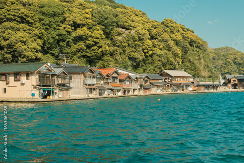 青く輝く海に並ぶ舟屋、豊かな緑の山を背景にした伊根の美しい風景
