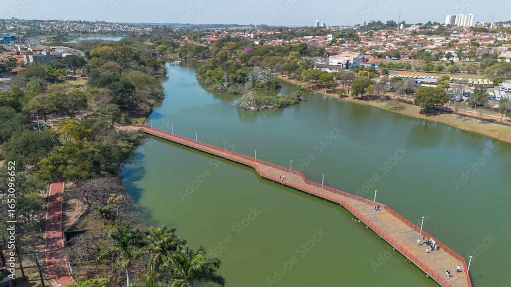 Fototapeta premium Aerial view of the lake and skyline of São José do Rio Preto, São Paulo, Brazil, showing urban buildings, waterfront, trees and blue sky on a sunny day.